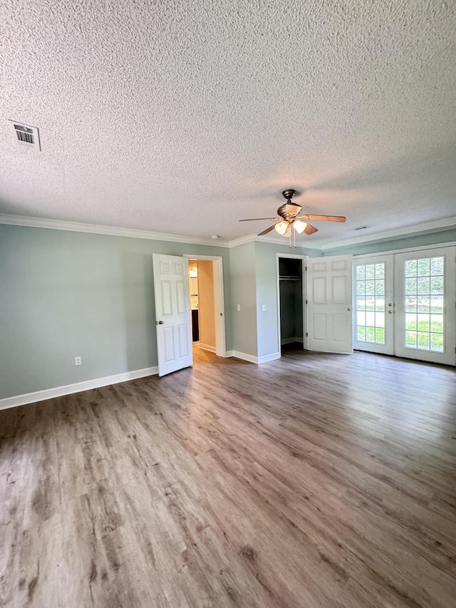 unfurnished living room with wood finished floors, a textured ceiling, ornamental molding, ceiling fan, and baseboards