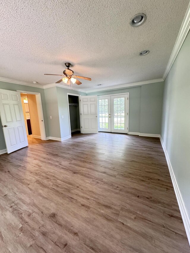 unfurnished living room featuring a textured ceiling, crown molding, wood finished floors, baseboards, and ceiling fan