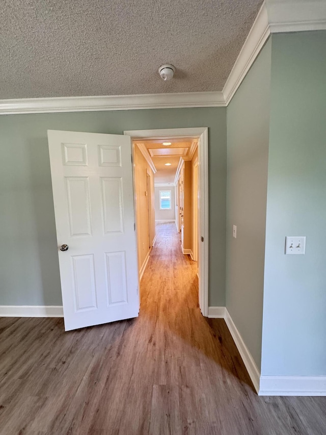 hall with ornamental molding, wood finished floors, baseboards, and a textured ceiling