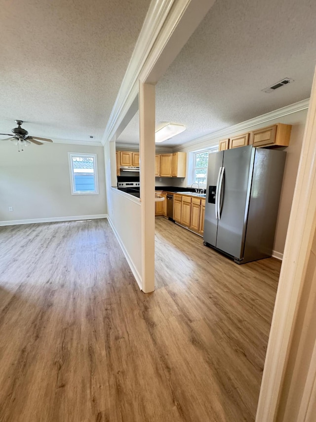 kitchen featuring stainless steel appliances, crown molding, a textured ceiling, light wood-type flooring, and baseboards