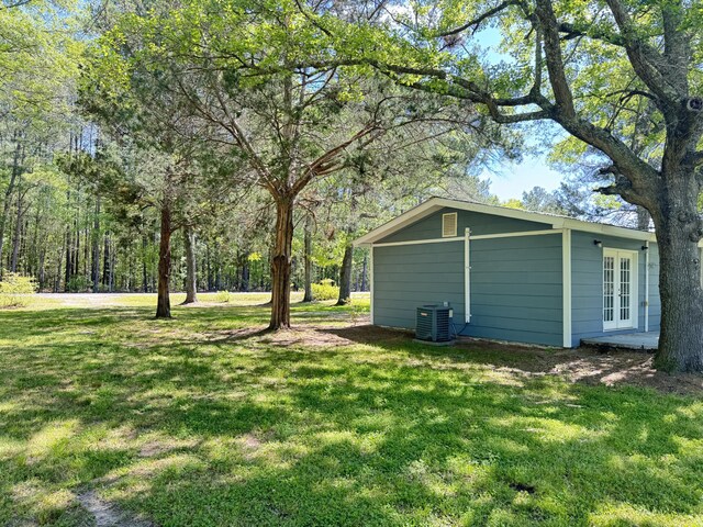 view of green lawn with french doors and central AC unit