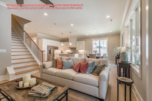 living room featuring ornamental molding, sink, and light hardwood / wood-style floors