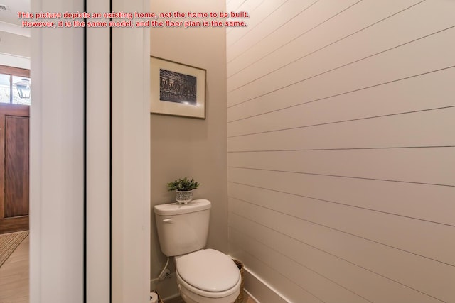 bathroom with toilet and wood walls