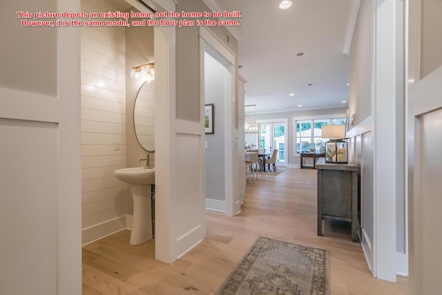 corridor featuring sink, ornamental molding, and light wood-type flooring