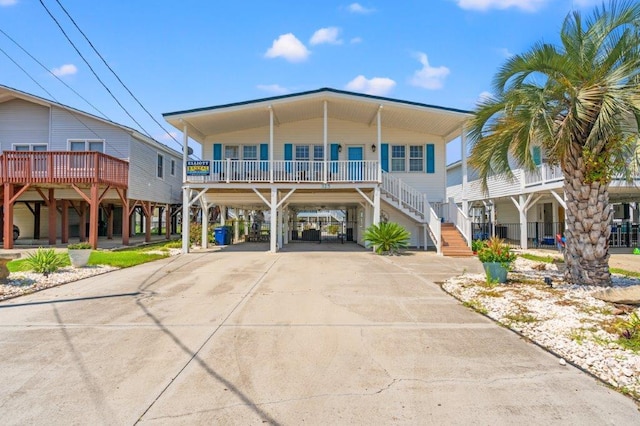 325 N 58th Ave, North Myrtle Beach, SC 29582 - raised beach house featuring a carport, concrete driveway, a porch, and stairs