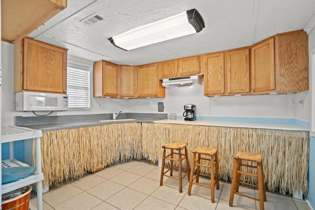 325 N 58th Ave, North Myrtle Beach, SC 29582 - kitchen with white microwave, under cabinet range hood, and light tile patterned floors