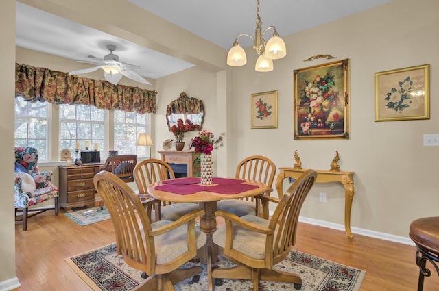 dining area with ceiling fan with notable chandelier and light wood-type flooring