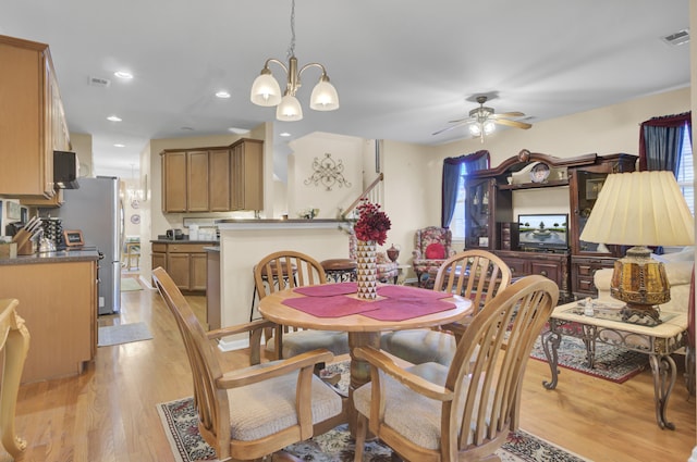 dining room featuring light hardwood / wood-style floors and ceiling fan with notable chandelier