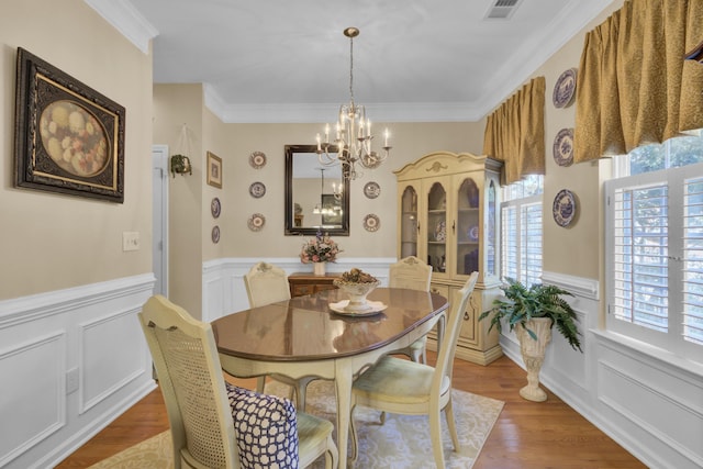 dining space with ornamental molding, a notable chandelier, and hardwood / wood-style flooring