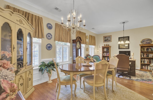 dining room with light hardwood / wood-style floors, a healthy amount of sunlight, an inviting chandelier, and crown molding