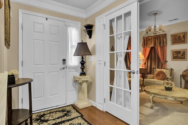 entrance foyer featuring hardwood / wood-style flooring, crown molding, and a chandelier