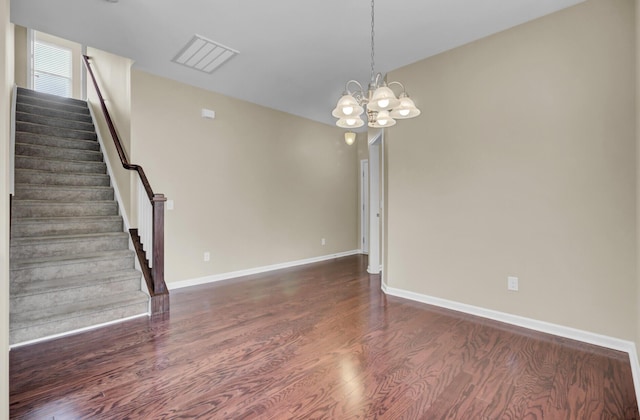 empty room featuring dark wood-type flooring and an inviting chandelier