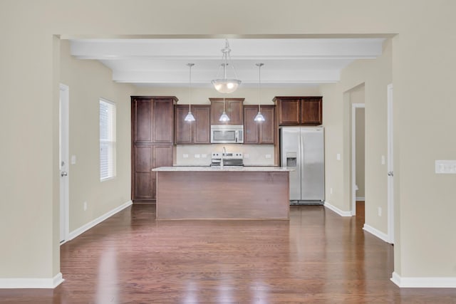 kitchen featuring appliances with stainless steel finishes, backsplash, beamed ceiling, hanging light fixtures, and an island with sink