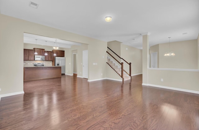 unfurnished living room featuring dark wood-type flooring and an inviting chandelier