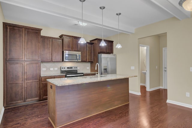 kitchen with sink, an island with sink, beamed ceiling, light stone counters, and stainless steel appliances