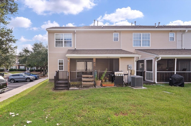 rear view of property featuring central air condition unit, a sunroom, and a yard