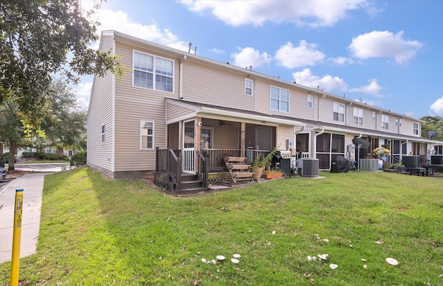 rear view of property with a lawn, a sunroom, and central AC unit