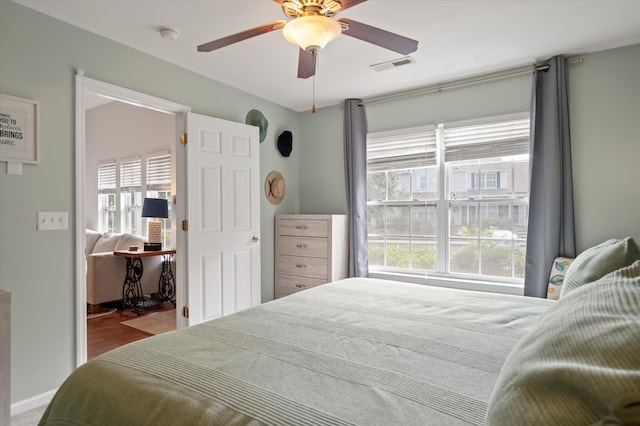 bedroom with multiple windows, hardwood / wood-style floors, and ceiling fan