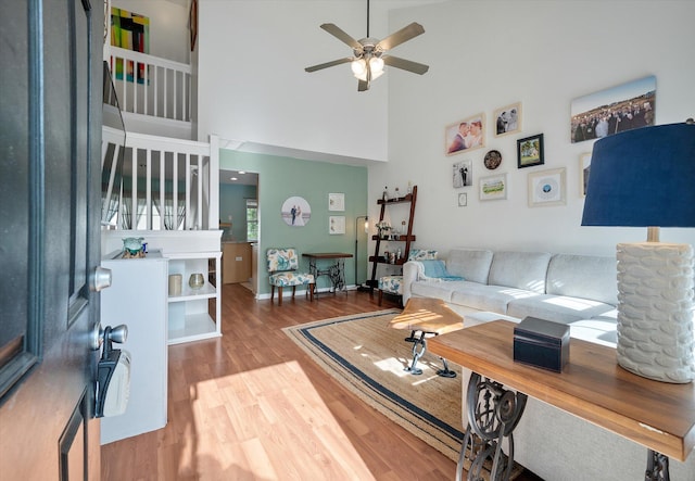 living room with ceiling fan, wood-type flooring, and a high ceiling