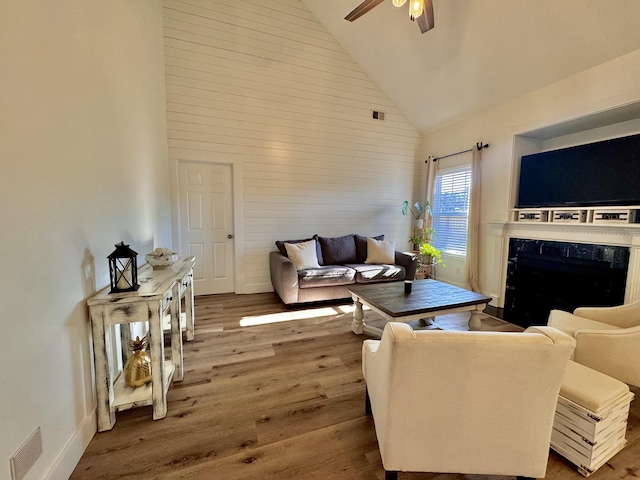 living room featuring high vaulted ceiling, wood-type flooring, a high end fireplace, and ceiling fan