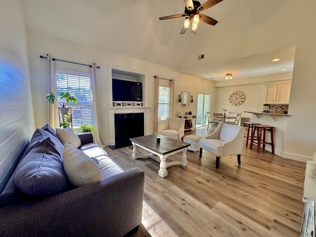 living room with light hardwood / wood-style floors, high vaulted ceiling, and ceiling fan