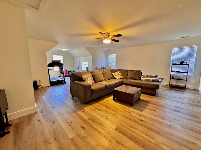 living room with light wood-type flooring, a textured ceiling, vaulted ceiling, and a wealth of natural light