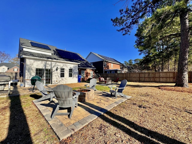 back of property with a patio area, an outdoor fire pit, and solar panels