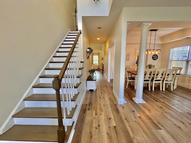 stairs with wood-type flooring and ornate columns