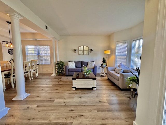 living room featuring ornate columns and light wood-type flooring