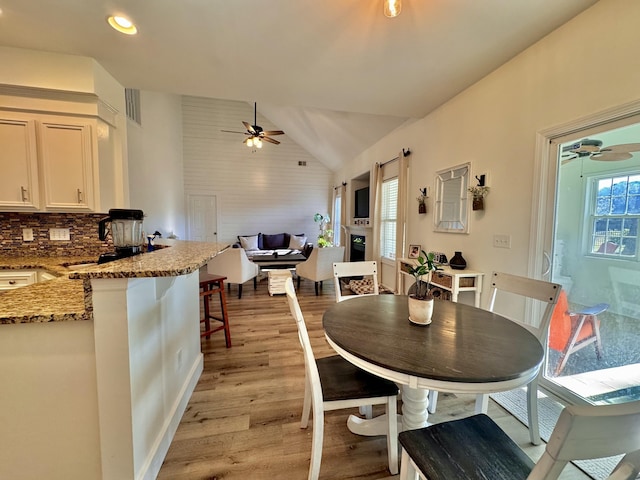 dining area featuring light wood-type flooring, vaulted ceiling, and ceiling fan