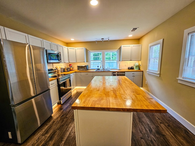 kitchen featuring stainless steel appliances, wood counters, a center island, white cabinetry, and dark hardwood / wood-style flooring