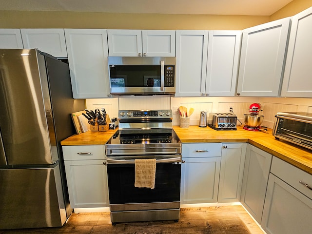 kitchen with light hardwood / wood-style flooring, butcher block countertops, white cabinets, and stainless steel appliances