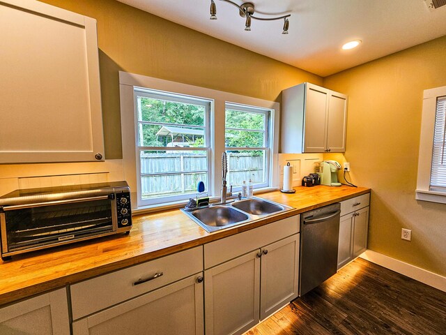 kitchen with butcher block counters, dark wood-type flooring, dishwasher, and track lighting