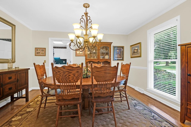 dining room with baseboards, visible vents, ornamental molding, wood finished floors, and an inviting chandelier