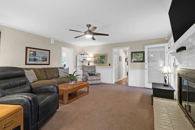 carpeted living room featuring ornamental molding, a brick fireplace, and a ceiling fan