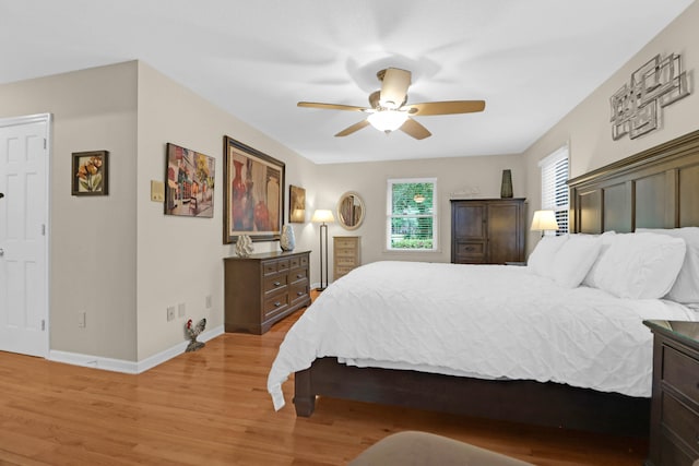 bedroom featuring light wood finished floors, a ceiling fan, and baseboards