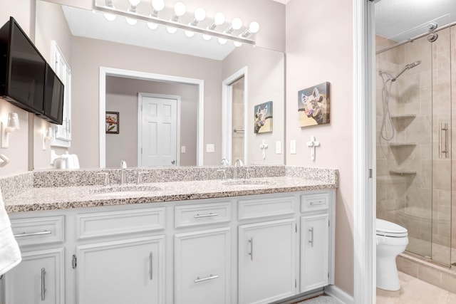 full bath featuring double vanity, a sink, toilet, and a shower stall