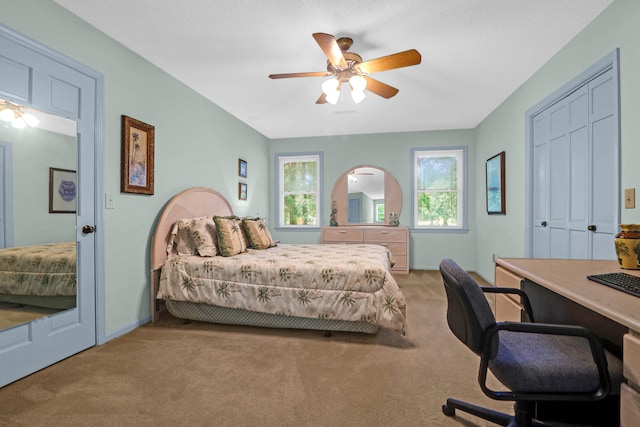 carpeted bedroom with arched walkways, a ceiling fan, and baseboards