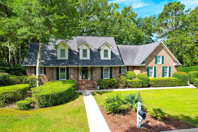 cape cod house with roof with shingles, a front lawn, and brick siding