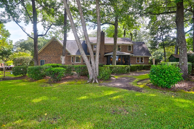 view of front of home with a front yard, a chimney, and brick siding