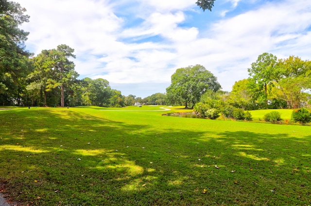 view of home's community with view of golf course and a yard