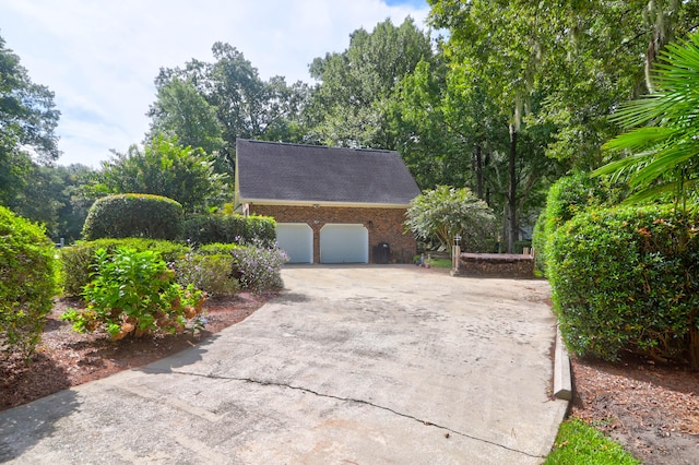 view of property exterior with a garage, concrete driveway, brick siding, and roof with shingles