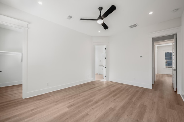 unfurnished bedroom with ceiling fan, a walk in closet, connected bathroom, and light wood-type flooring