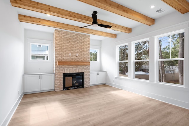 unfurnished living room featuring beamed ceiling, ceiling fan, a fireplace, and light hardwood / wood-style floors