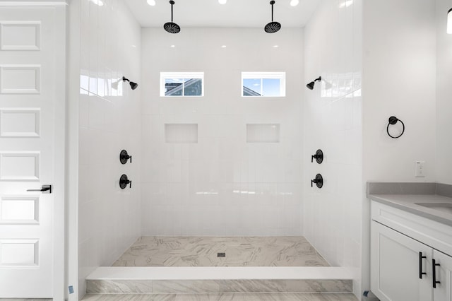 bathroom with a tile shower and vanity