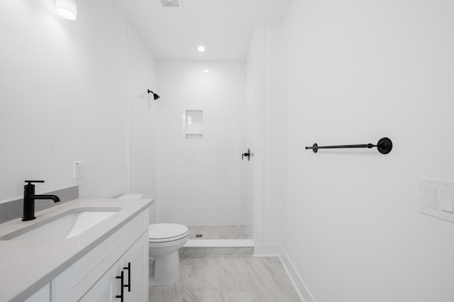 bathroom featuring a tile shower, vanity, and toilet