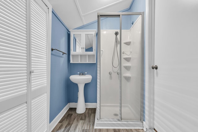 bathroom with a shower stall, wood finished floors, baseboards, and lofted ceiling