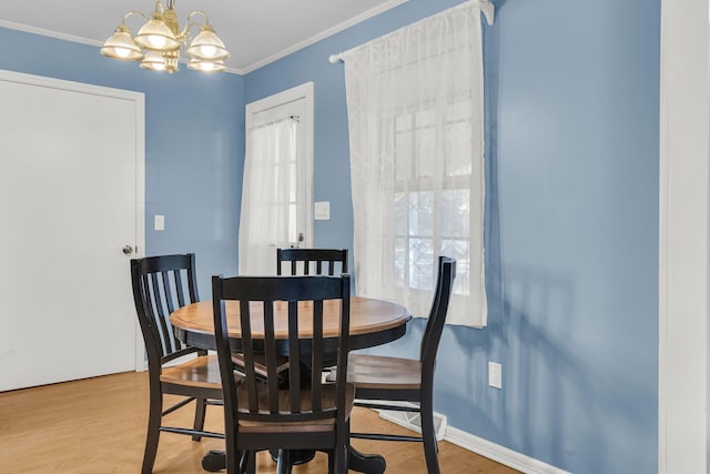 dining space with baseboards, a notable chandelier, wood finished floors, and ornamental molding