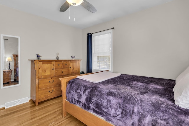 bedroom featuring light wood-style flooring, baseboards, visible vents, and ceiling fan