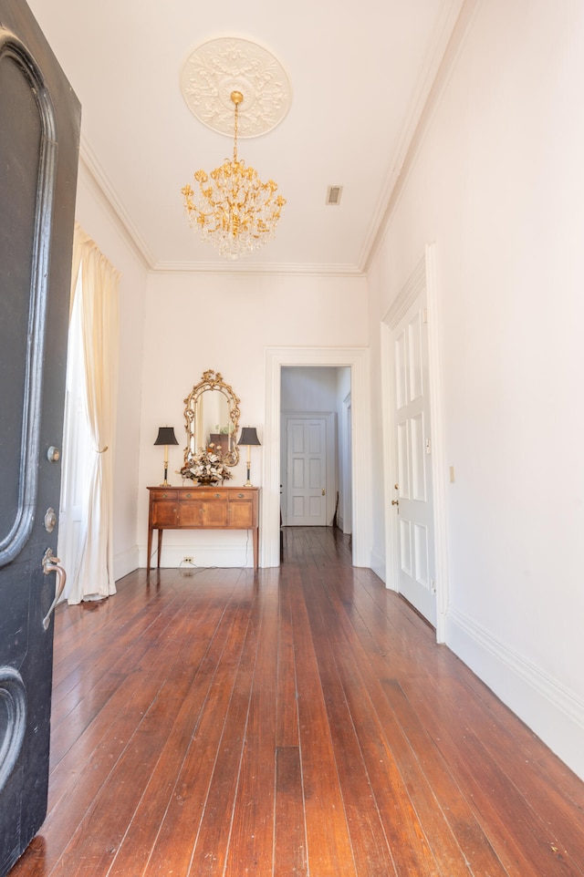 foyer entrance featuring dark hardwood / wood-style floors, crown molding, and a chandelier